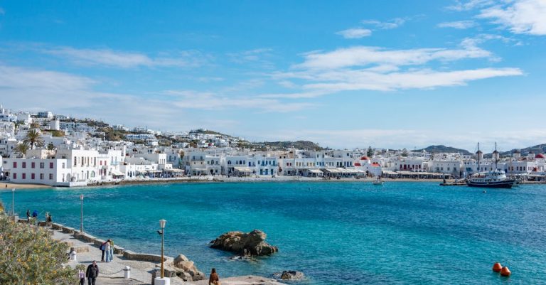 Beautiful view of Mykonos town with people strolling by the blue Aegean Sea.