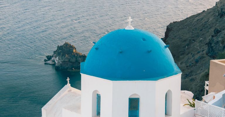 Stunning view of a blue-domed church in Santorini with breathtaking coastal scenery.