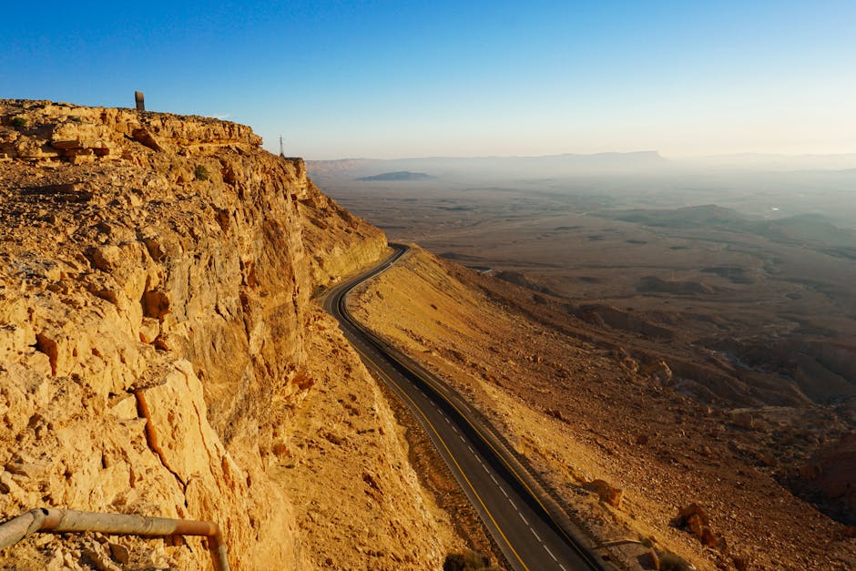 Explore the breathtaking arid landscape of the Mitzpe Ramon Crater with a winding road and expansive desert views.